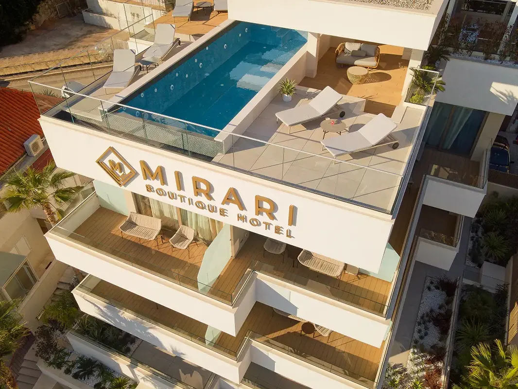 Bird view of Boutique Hotel Mirari with rooftop infinity pool, two lounge chairs and cocktails.
