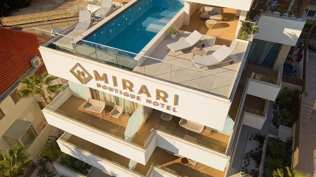 Bird view of Boutique Hotel Mirari with rooftop infinity pool, two lounge chairs and cocktails.