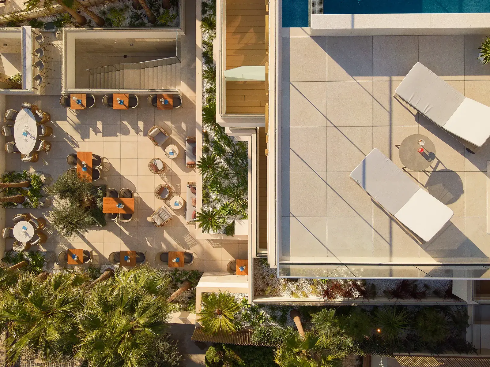 Aerial view of the hotel rooftop terrace, featuring lounge chairs, a dining area, and landscaping