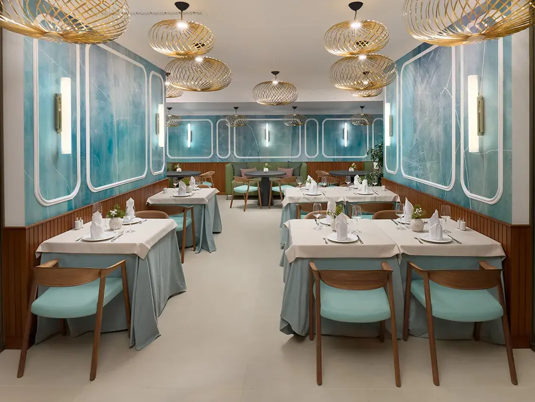 Interior of restaurant Mirari, with blue walls, golden lamps and dark wooden chairs