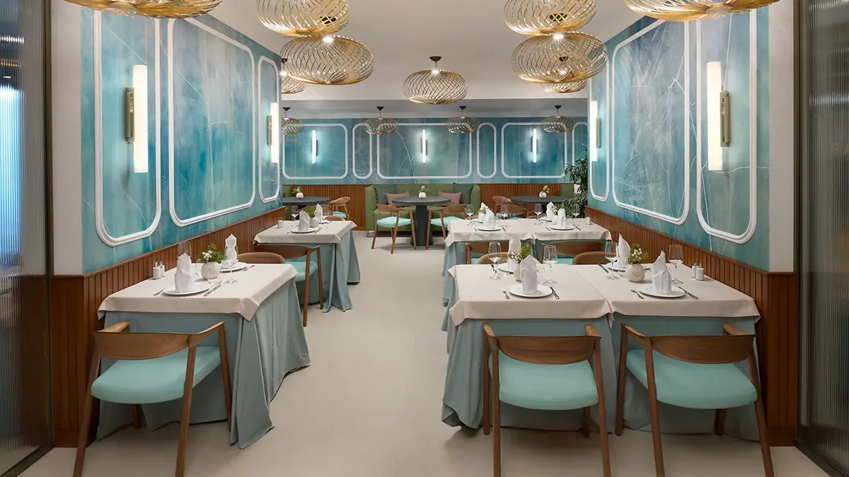 Interior of restaurant Mirari, with blue walls, golden lamps and dark wooden chairs