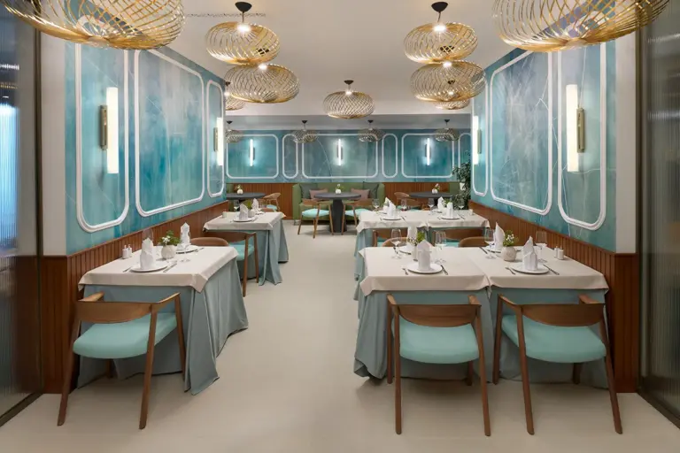 Interior of restaurant Mirari, with blue walls, golden lamps and dark wooden chairs