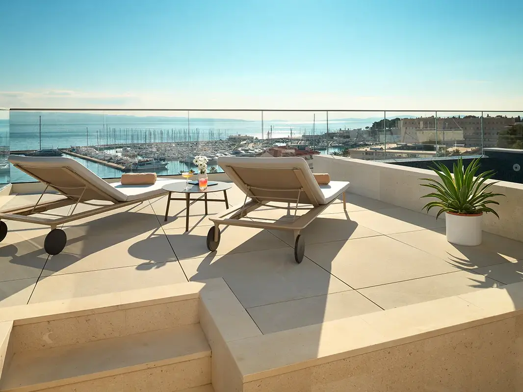 Sea view from the hotel rooftop with pool, lounge chairs and cocktails