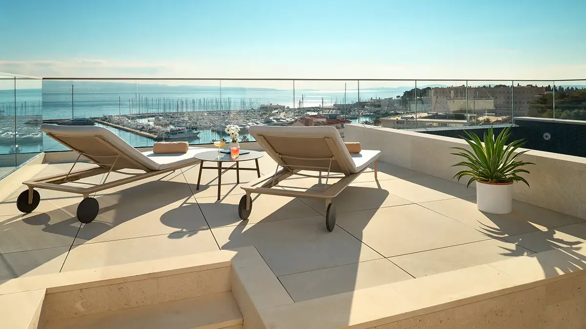 Sea view from the hotel rooftop with pool, lounge chairs and cocktails