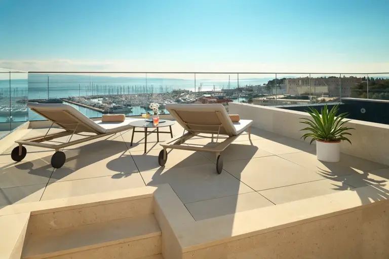 Sea view from the hotel rooftop with pool, lounge chairs and cocktails