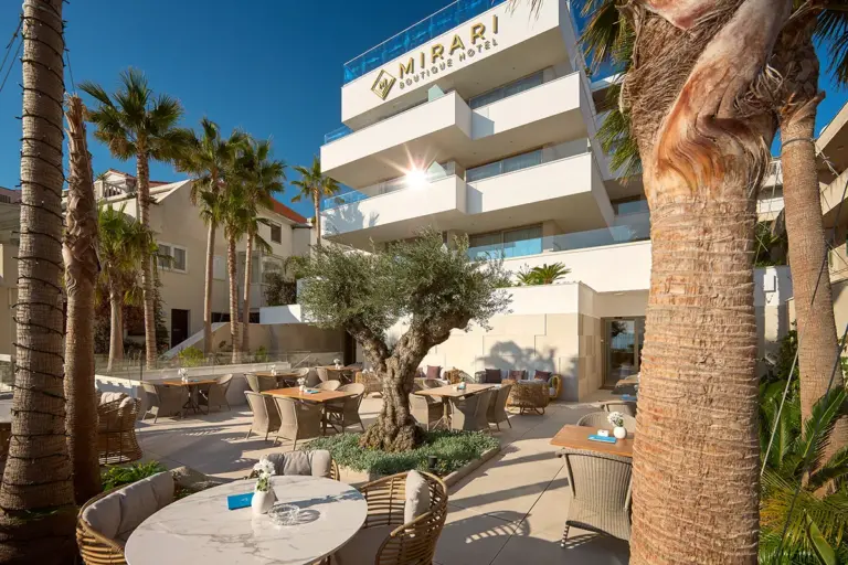 Restaurant terrace with palms, olive tree and a variety of plants in front of Boutique Hotel Mirari,